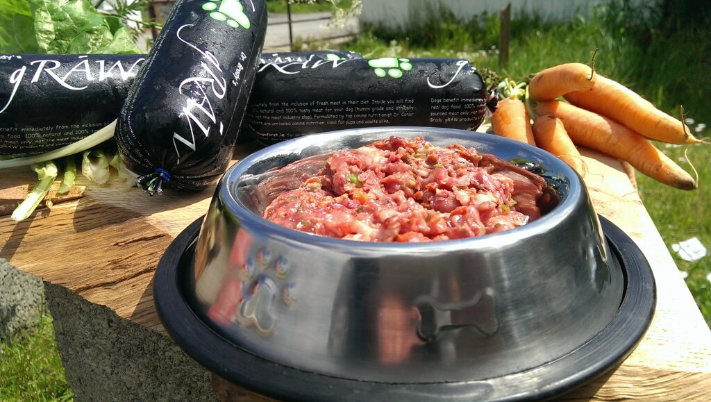 A bowl of raw dog food with some Graw Dog Food chubs beside it