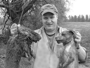 Terrierman Pat Burns holding up a groundhog and jack russel by the scruff of the neck